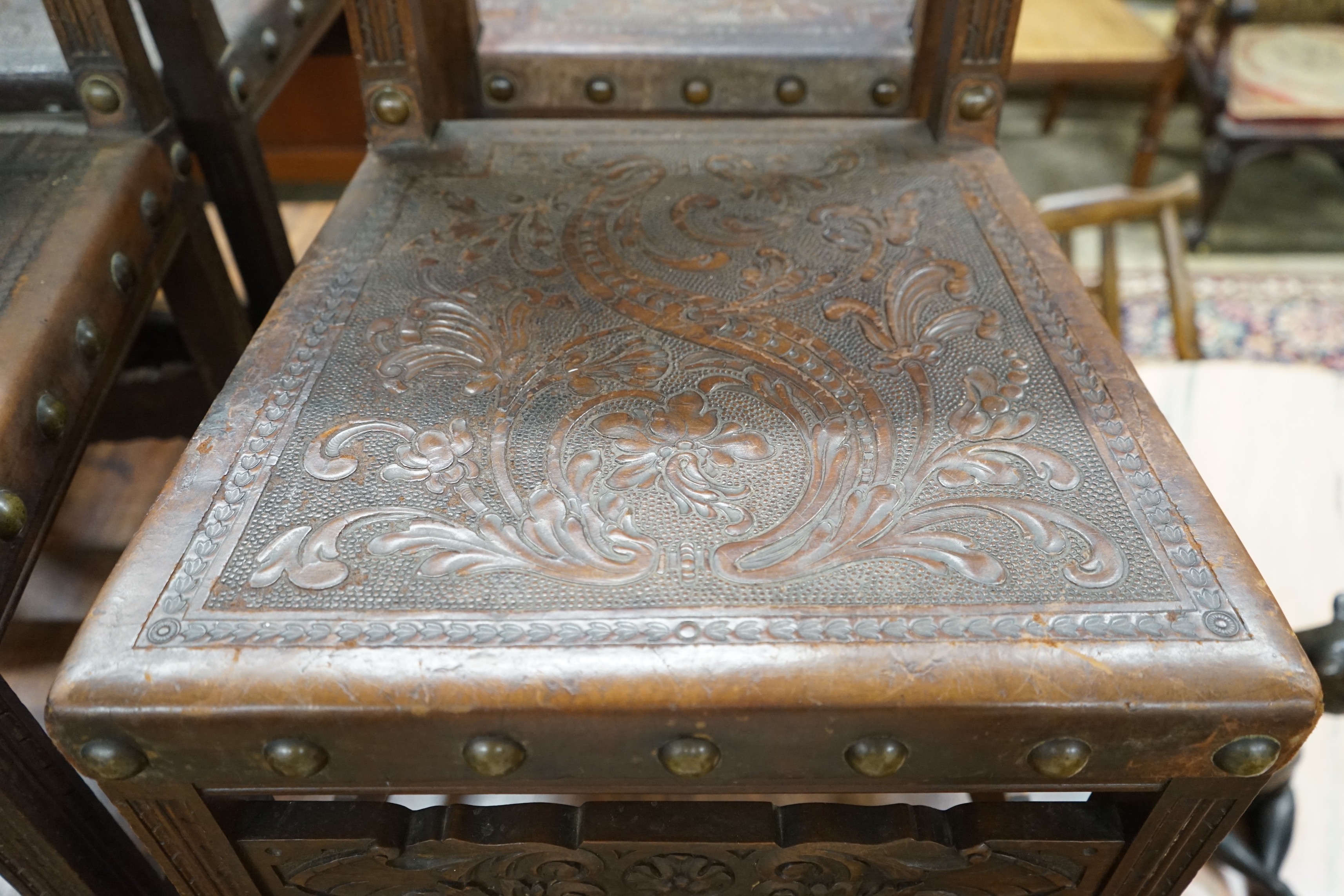 A set of six 18th century style brass studded carved oak and embossed leather dining chairs